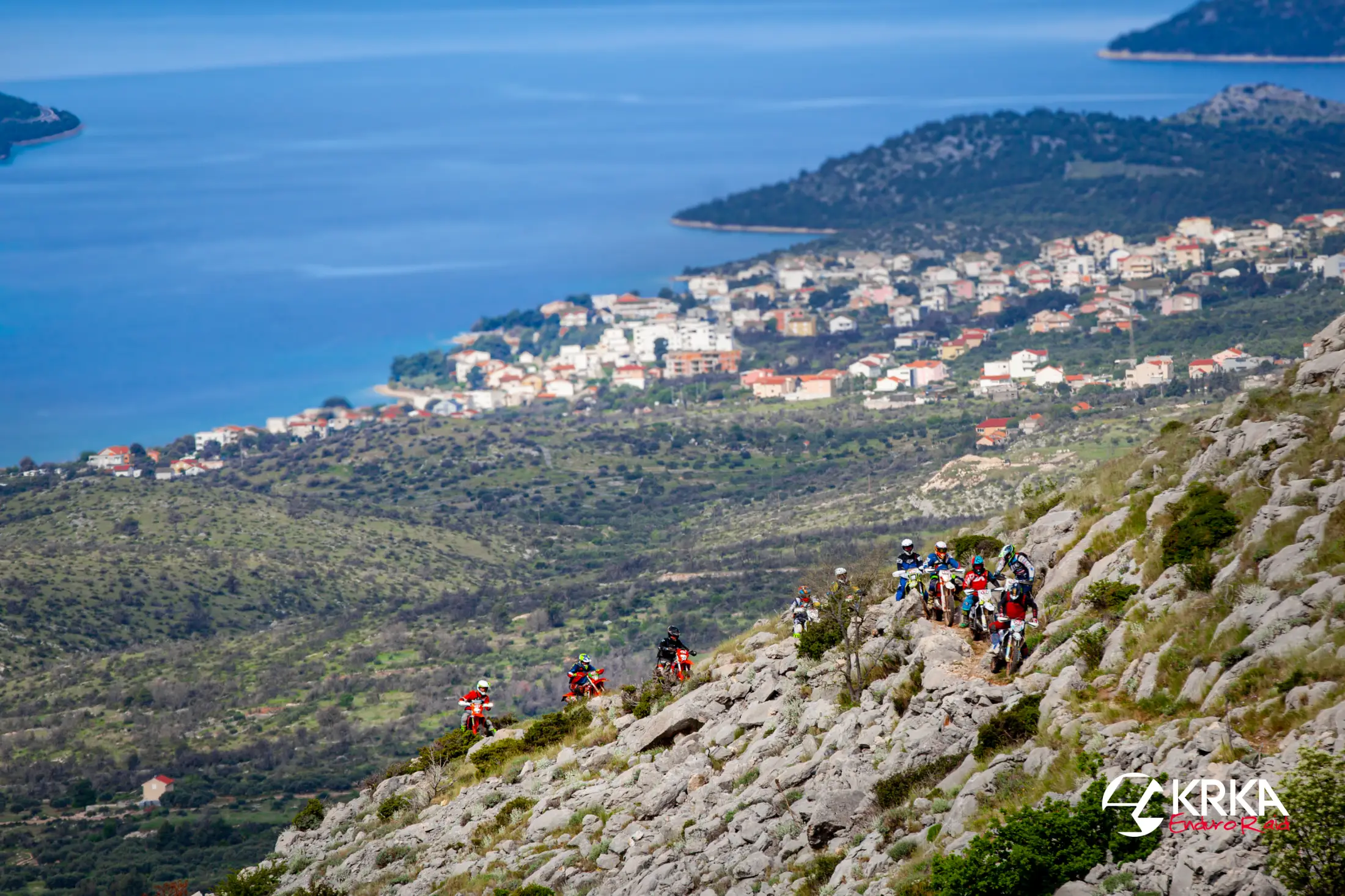 Due piloti enduro su una pietraia sopra il mare di Primošten